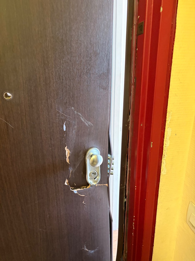 Serrure multipoints exposée sur porte en bois déformée après tentative d'effraction